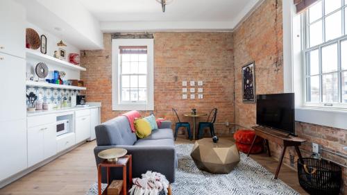a living room with a blue couch and a brick wall at Pickle Factory - Odd Fellows Hall in Covington