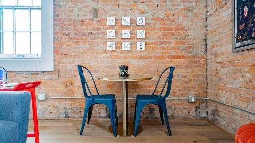 a table with two blue chairs and a brick wall at Pickle Factory - Odd Fellows Hall in Covington