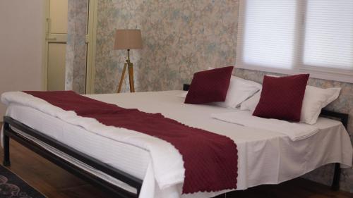 a large bed with red and white sheets and pillows at The Green Arc in Gurgaon