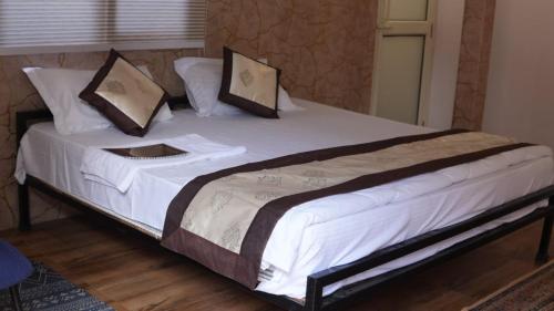 a large bed with white sheets and pillows on it at The Green Arc in Gurgaon