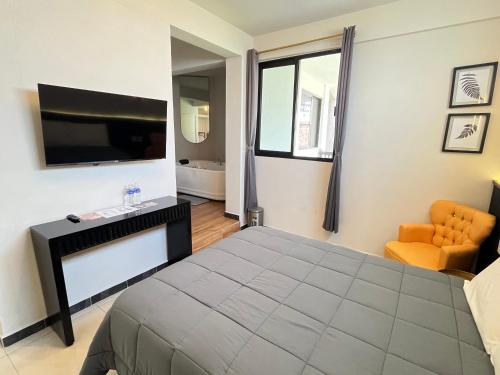 a bedroom with a bed and a tv and a chair at HOTEL BOUTIQUE ÁRBOL De LA VIDA in Taxco de Alarcón