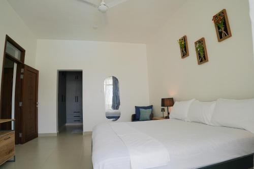 a bedroom with a large white bed with pictures on the wall at The Nest at Baobab Waves in Mombasa