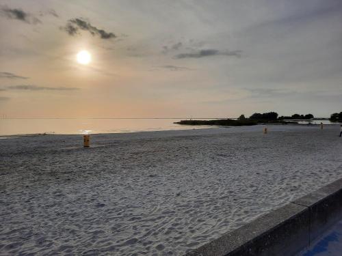 a beach with the sun setting on the sand at Chalet V14 4pers in Makkum