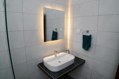 a white bathroom with a sink and a mirror at The Nest at Baobab Waves in Mombasa