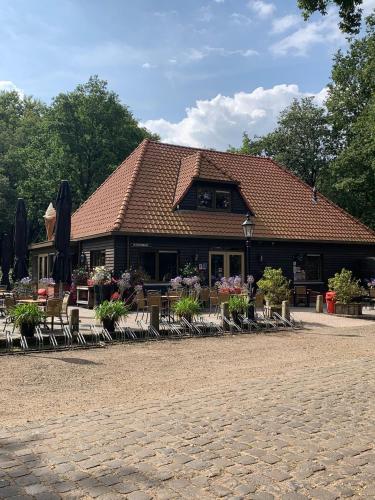a building with chairs and umbrellas in front of it at Casa Elixa prachtige stacaravan met heerlijke overkapping in Eext