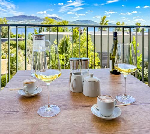 a table with two glasses of white wine on a balcony at Apartmán s krásným výhledem na jezera a Pálavu in Pasohlávky