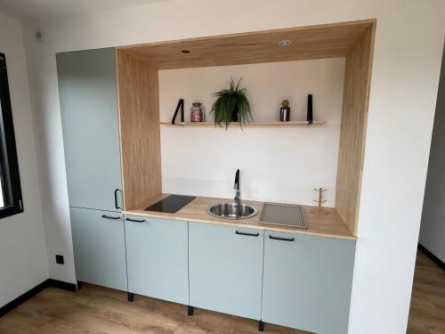 a kitchen with white cabinets and a sink at Maison 2 chambres avec terrasse in Doullens