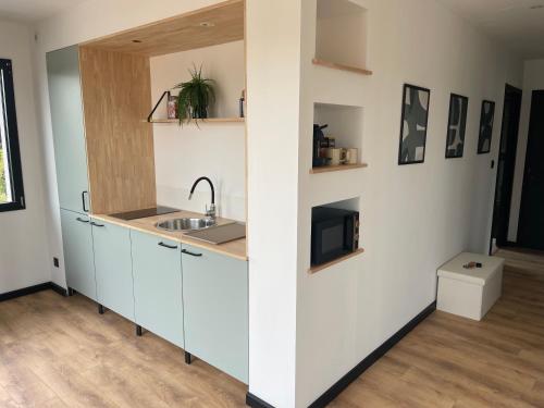 a kitchen with white cabinets and a sink at Maison 2 chambres avec terrasse in Doullens