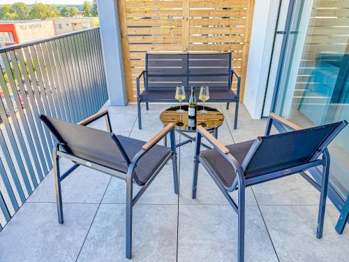 two chairs and a table with wine glasses on a balcony at Apartmán s krásným výhledem na jezera a Pálavu in Pasohlávky