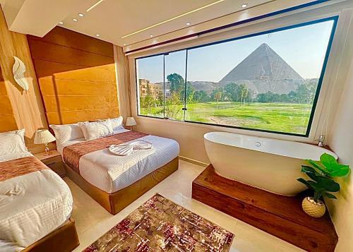 a bedroom with a view of the pyramids from a window at Joia Pyramids View Hotel in Cairo