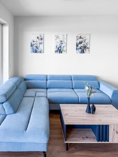 a blue couch in a living room with a table at Apartmán s krásným výhledem na jezera a Pálavu in Pasohlávky