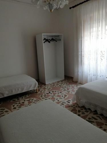 a white room with two beds and a window at La Casa di Carola in San Fratello