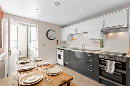 a kitchen with a table with plates on it at Hosted by StaySejour - 7Beds - Town House - Free Parking - outside space in Brighton & Hove