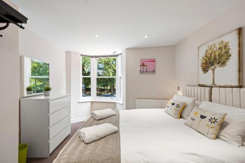 a white bedroom with a large bed and two windows at Hosted by StaySejour - 7Beds - Town House - Free Parking - outside space in Brighton & Hove