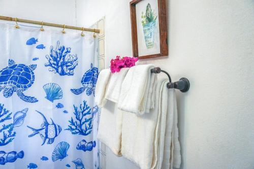 a bathroom with a blue and white shower curtain and towels at Tropical Retreat in Matthews