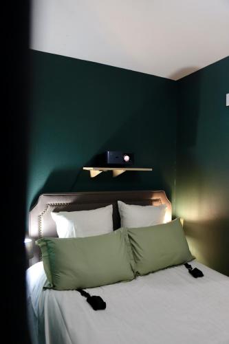 a bedroom with a green wall and a bed with pillows at LoveRoom La Petite Suite avec SPA in Brest