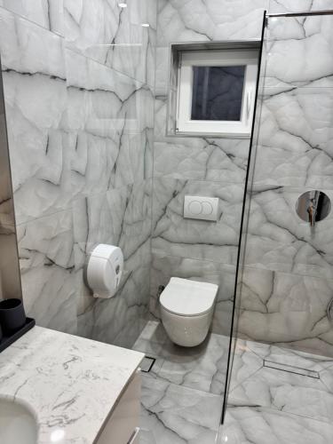 a white bathroom with a toilet and a window at London Restaurant Hotel in Kukës