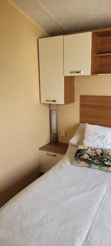 a bedroom with a bed with white sheets and cabinets at Willerby Delux - Holiday Home by the Sea - close to the Entertainment Complex-bedding, towels & wifi Included! in Jaywick Sands