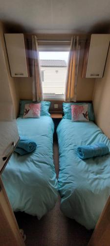 two beds in a small room with a window at Willerby Delux - Holiday Home by the Sea - close to the Entertainment Complex-bedding, towels & wifi Included! in Jaywick Sands