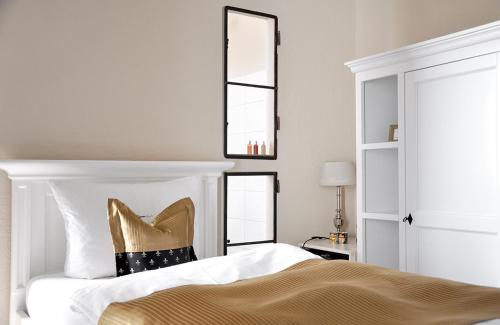 a bedroom with a bed with a gold pillow and a mirror at Klosterhotel Neuzelle in Neuzelle