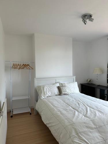 a white bedroom with a bed and a lamp at Week and Month Stays 3 Bed Flat and Cinema Room in Rogerstone