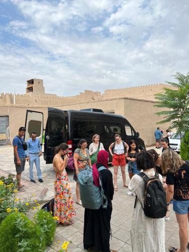 un grupo de personas de pie delante de una furgoneta en Zukhro Boutique Hotel, en Khiva