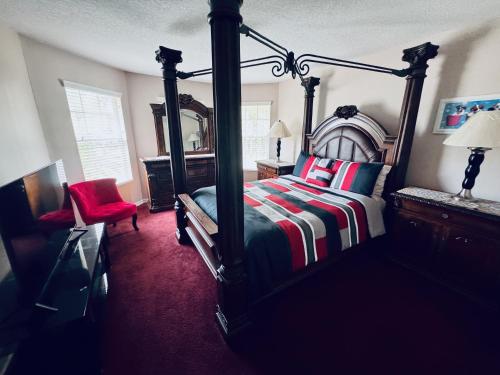 a bedroom with a canopy bed and a red chair at Beautiful Pool Home near the I95 Exit 284 in Palm Coast