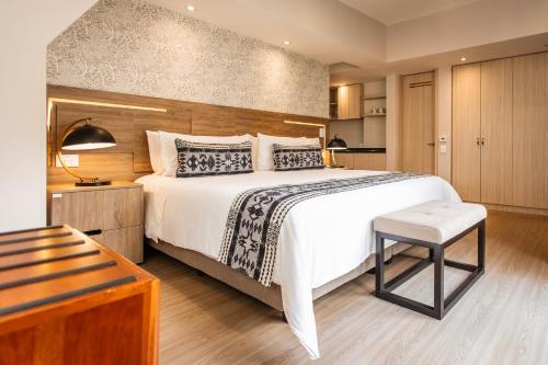 a bedroom with a large bed and a chair at Hotel Portón de la Cabrera in Bogotá