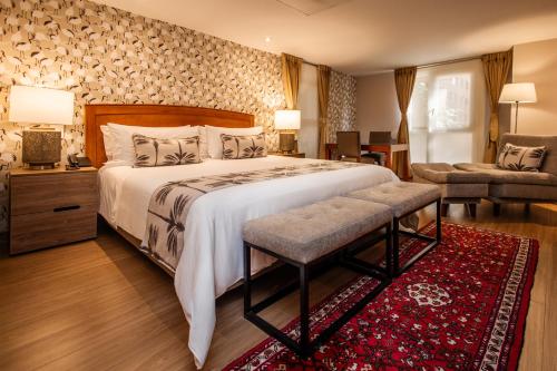 a bedroom with a large bed with a red rug at Hotel Portón de la Cabrera in Bogotá