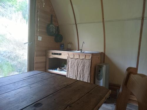 a kitchen with a wooden table and a fireplace at Cabane écologique au bord de l'eau in Laboule