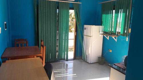a kitchen with blue walls and a table and a refrigerator at Ramirez in Encarnación