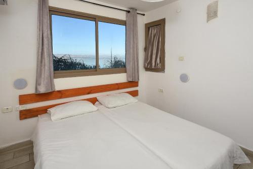 a bedroom with two white beds and a window at the royal lake views in Tiberias