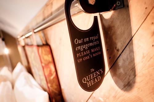 a sign is hanging on a wall at The Queen's Head in Kingston upon Thames