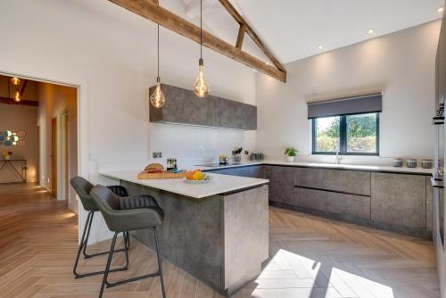 a kitchen with white walls and a concrete island with bar stools at Daisys Barn in Mattishall