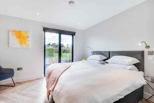 a white bedroom with a large bed with white pillows at Daisys Barn in Mattishall