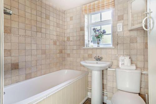 une salle de bain avec une baignoire, un lavabo et des toilettes dans l'établissement Coach House Cottage Annexe, à Wickham Market