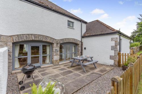 a patio with a grill in front of a house at 2 Bed in Newtonmore oc-d32413 in Newtonmore