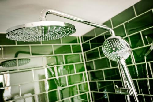 a shower head in a bathroom with green tiles at The Queen's Head in Kingston upon Thames
