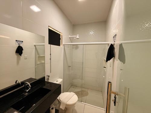 a white bathroom with a shower and a toilet at Village Comfort Hotel in Canindé de São Francisco