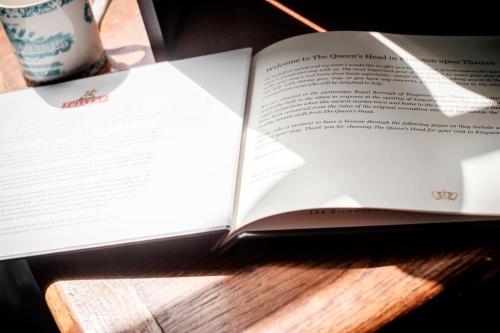an open book on a wooden table with a coffee mug at The Queen's Head in Kingston upon Thames