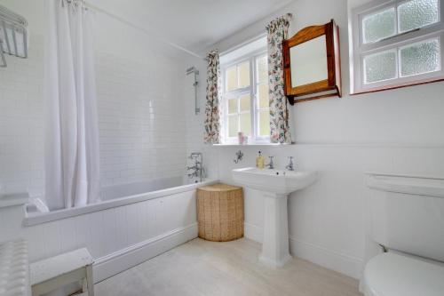a white bathroom with a sink and a tub and a toilet at Mill Cottage in Ufford