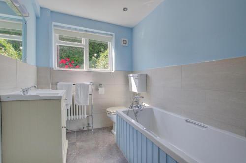 ein Badezimmer mit Badewanne und Toilette und einem Fenster in der Unterkunft Smugglers Cottage in Southwold
