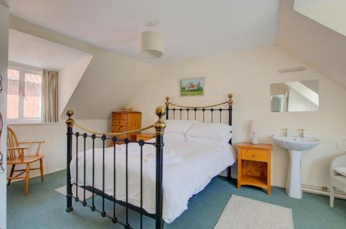ein Schlafzimmer mit einem schwarzen Bett und einem Waschbecken in der Unterkunft Smugglers Cottage in Southwold