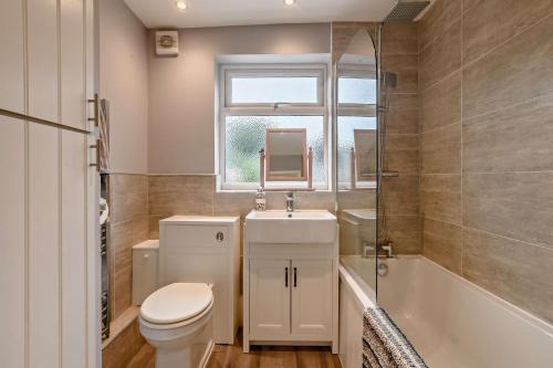 a bathroom with a toilet and a sink and a tub at Paddington Cottage - Dersingham in Dersingham