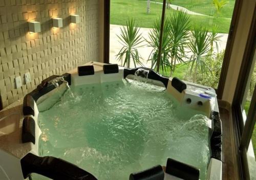 a jacuzzi tub in a bathroom with a window at VG Sun Cumbuco - Praia e Tranquilidade in Caucaia