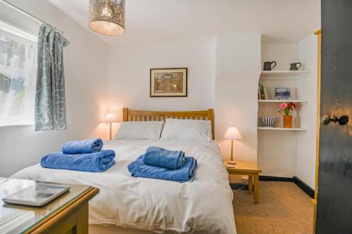 ein Schlafzimmer mit einem Bett mit blauen Kissen darauf in der Unterkunft Dart Cottage in Aldeburgh