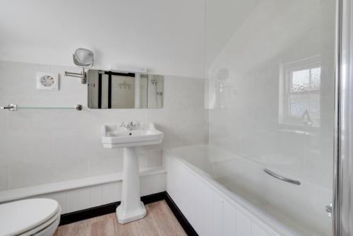 ein weißes Badezimmer mit Toilette und Waschbecken in der Unterkunft Dart Cottage in Aldeburgh