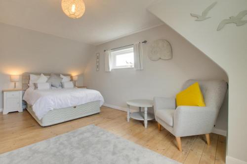 a bedroom with a bed and a chair and a window at Fallowfield in Reydon