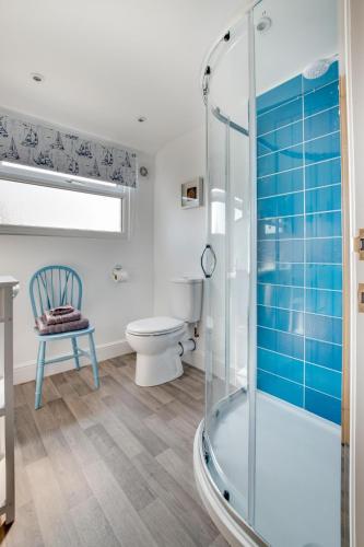 a bathroom with a shower and a toilet and a chair at Loxwood in Reydon