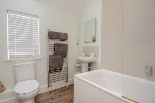 a white bathroom with a toilet and a sink at Pembroke Cottage in Walberswick
